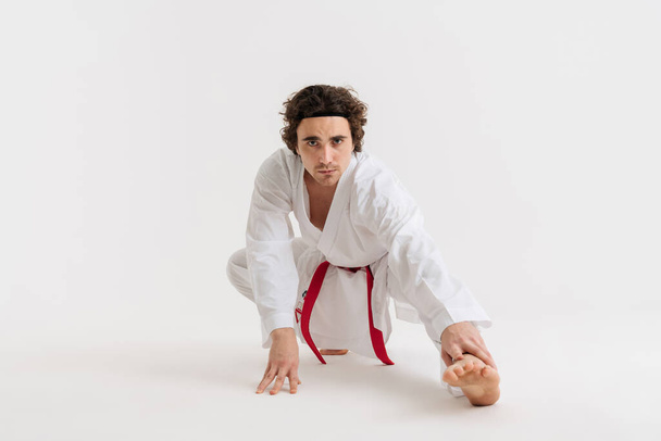 Confident young karate man warming up isolated over white background - Foto, Bild