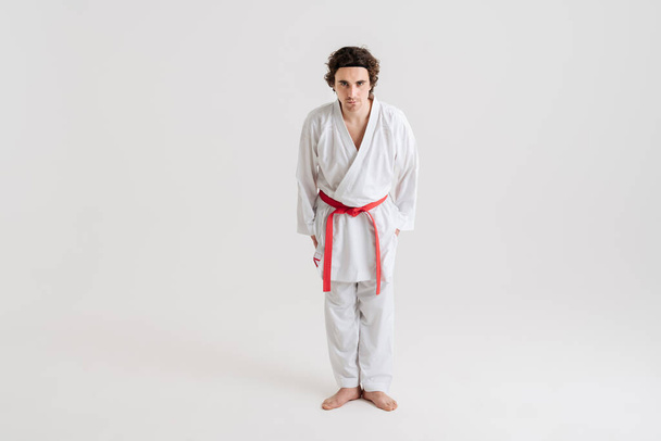 Young caucasian sportsman dressed in kimono practice in karate isolated over white background - Fotó, kép