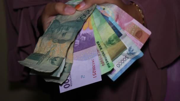 Hand met Indonesische munt, 100000, 50000. 20000, 10000, 2000 roepia bankbiljetten  - Video