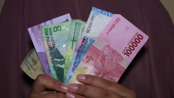 Mano sosteniendo moneda indonesia, 100000, 50000. Billetes de 20000, 10000, 2000 rupias  - Metraje, vídeo