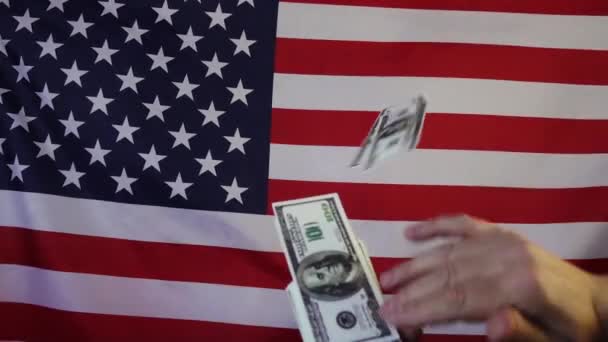 Πτώση δολαρίων στο φόντο της αμερικανικής σημαίας σε αργή κίνηση. Βροχή χρήματος. - Πλάνα, βίντεο