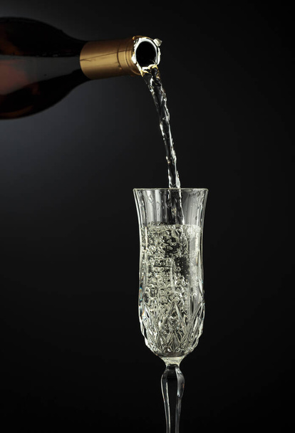 Sparkling wine is poured from a bottle into a glass. Copy space. - Fotografie, Obrázek