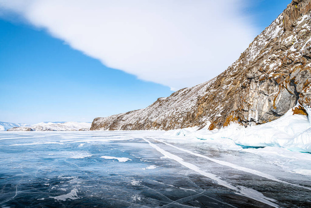 Long, sinuous cracks extend beyond the horizon on the dark, endless ice of Lake Baikal - Photo, image