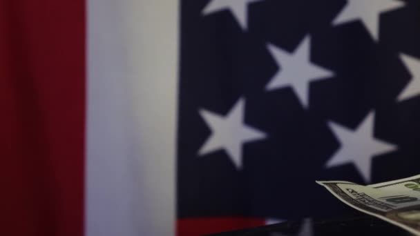 Egy játékprotézis egy dollárszámlát tart a fogai között az amerikai zászló hátterében. . - Felvétel, videó