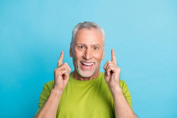 Portrait of attractive cheerful grey-haired man pointing forefingers up copy space isolated over bright blue color background - Foto, immagini
