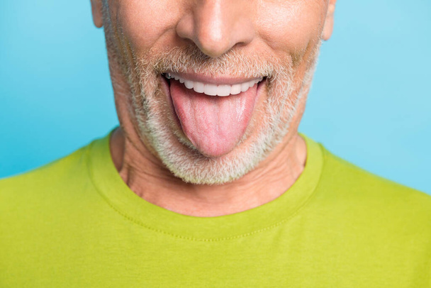 Cropped close-up portrait of attractive cheerful glad bearded grey-haired man showing tongue out isolated over bright blue color background - Fotoğraf, Görsel