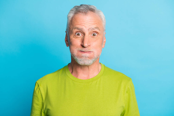 Photo of positive aged man holding breath pouted cheeks look camera isolated on blue color background - Фото, изображение