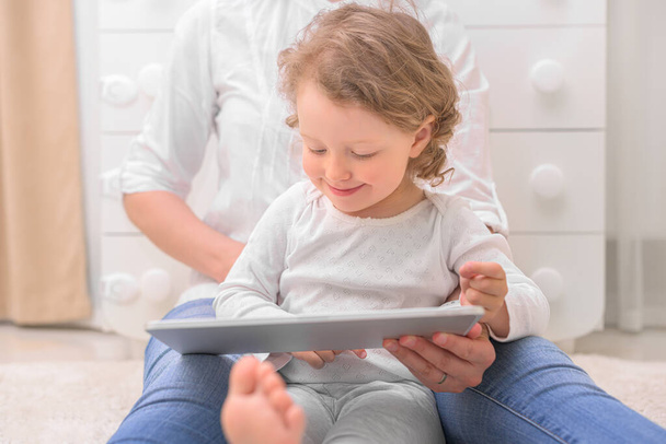 A little girl with her mother looks at the tablet computer. - Foto, Bild
