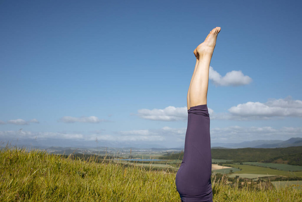 Una mujer en leggins morados sobre un fondo de montañas.Tiempo de yoga - Foto, Imagen