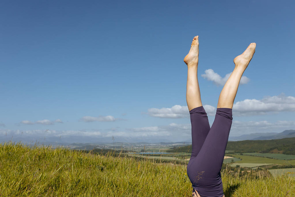 Una mujer en leggins morados sobre un fondo de montañas.Tiempo de yoga - Foto, Imagen