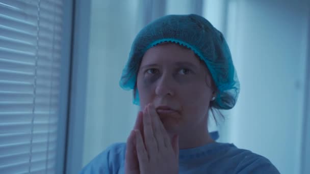 Stressaantunut nainen, joka itkee ja rukoilee sairaalassa ennen leikkausta. Huolestunut potilas klinikalla, jolla on tarttuneet kädet, pyytää Jumalalta apua. Henkilö onnettomuuden jälkeen peloissaan ja rukoilee ambulanssissa - Materiaali, video