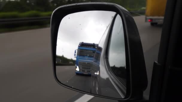 Driving on German highway on a rainy day - view through rear-view mirror - Séquence, vidéo