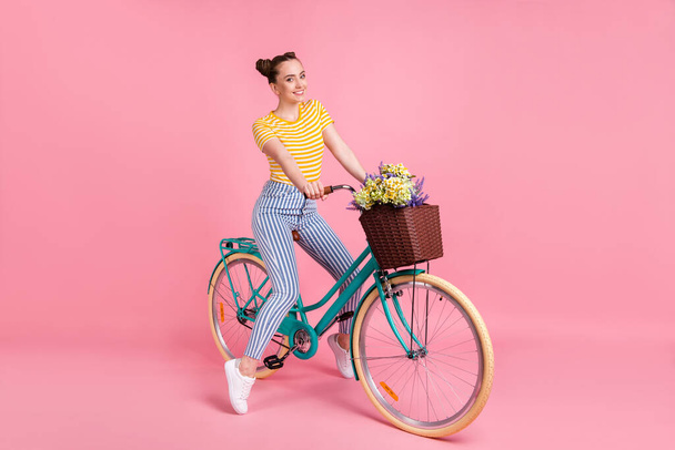 Full size profile photo of optimistic nice brunette lady ride bicycle wear yellow t-shirt pants sneakers isolated on pink color background - Zdjęcie, obraz