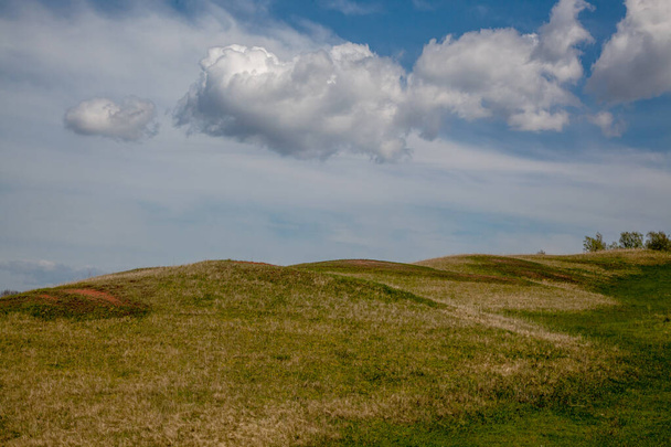 Hilly area on a summer day. Most of the frame is taken by the sky with beautiful clouds. - Photo, image