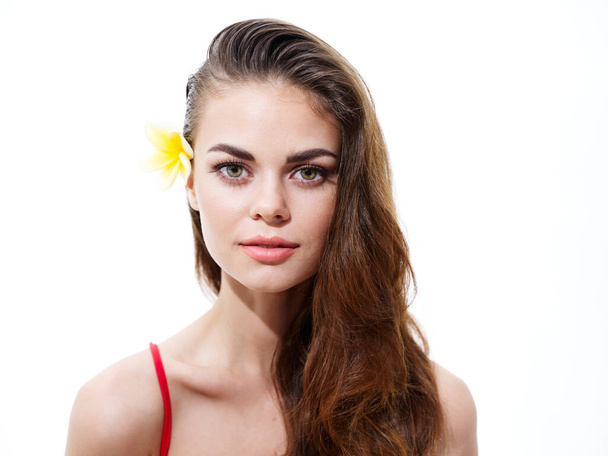portrait of an attractive woman with a flower in her hair brunette naked shoulders red t-shirt - Photo, Image