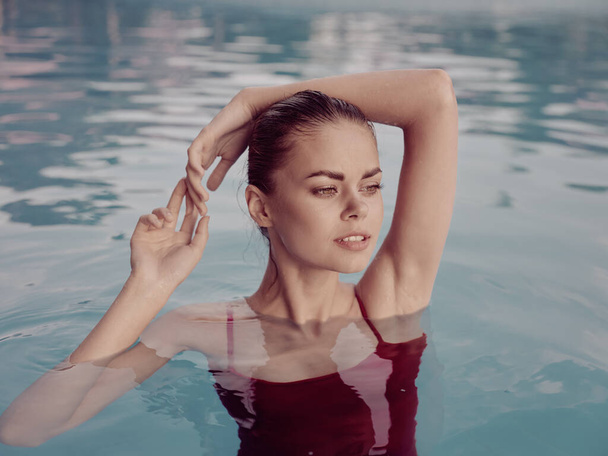 csinos nő piros fürdőruhában a medencében luxus kezek fej felett - Fotó, kép