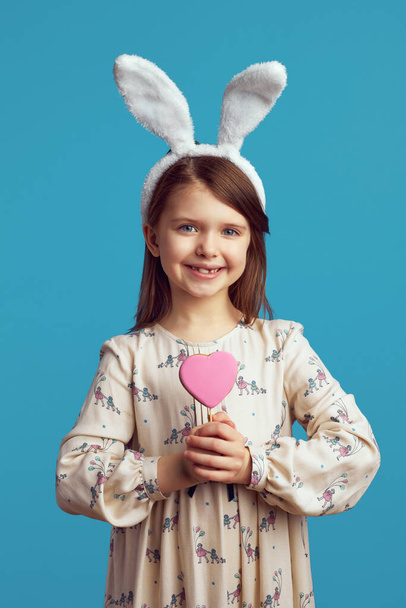 Roztomilá holčička se usmívá a drží sušenku ve tvaru srdce - Fotografie, Obrázek