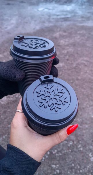 due tazze di caffè in mano al parco invernale. Foto di alta qualità - Foto, immagini