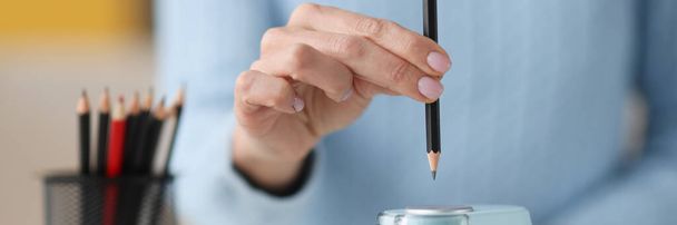 Female hands sticking out pencil in electronic sharpener closeup - Photo, Image