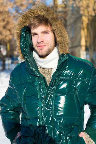 Hava değişikliklerine hazır. Kış stili erkek giyim. Kış kıyafeti. Tıraşsız bir adam kürklü, karlı bir geçmişi olan kalın bir ceket giyer. Adam kürklü kapüşonlu kışlık ceket giyiyor. Hipster kış modası - Fotoğraf, Görsel