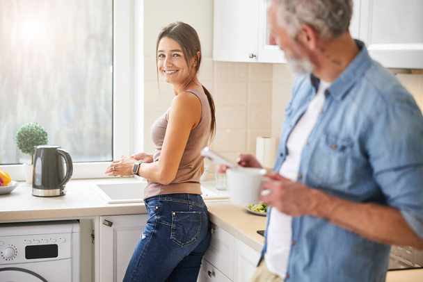 Happy cheerful female looking to her husband in the kitchen - Fotoğraf, Görsel