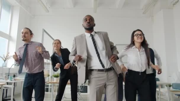 Група бізнесменів, що стоять в офісній кімнаті, рухаються руками, танцюють усміхнений погляд на камеру
 - Кадри, відео