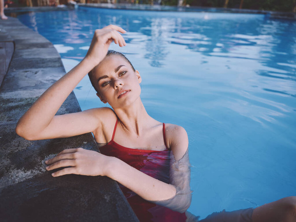 sexy donna in costume da bagno rosso appoggiato sulla piastrella e acqua limpida in piscina - Foto, immagini