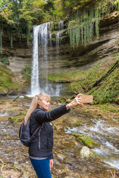 Tourist taking a selfie with the Cascade du Dard Nozon Gorge, near Croy Romainmtier, Canton Vaud, Switzerland. - Foto, imagen