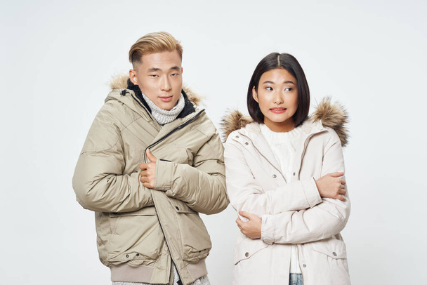 Mann und Frau in Winterjacken asiatisches Aussehen Licht Hintergrund ausgeschnitten Ansicht - Foto, Bild