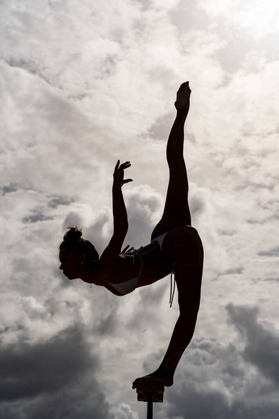 Silhouette of flexible woman keep balance on one leg in split. Yoga and healthy lifestyle concept  - 写真・画像