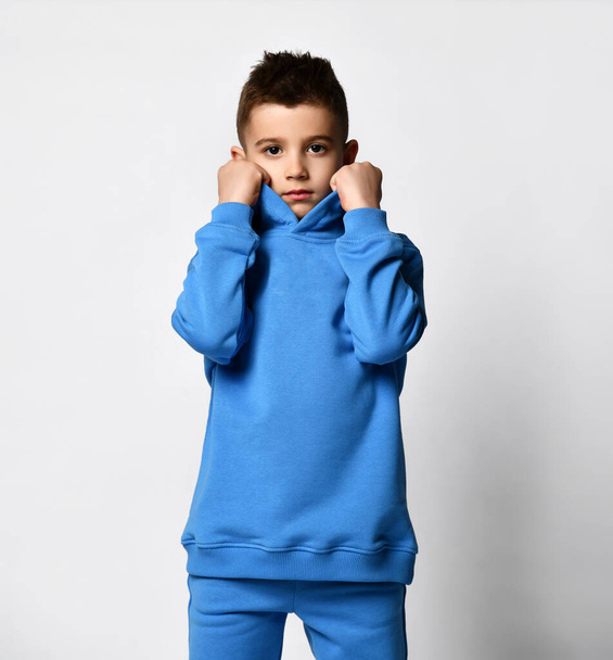 Studio portrait of a little boy in a trendy blue sports suit on a white background. - Foto, imagen