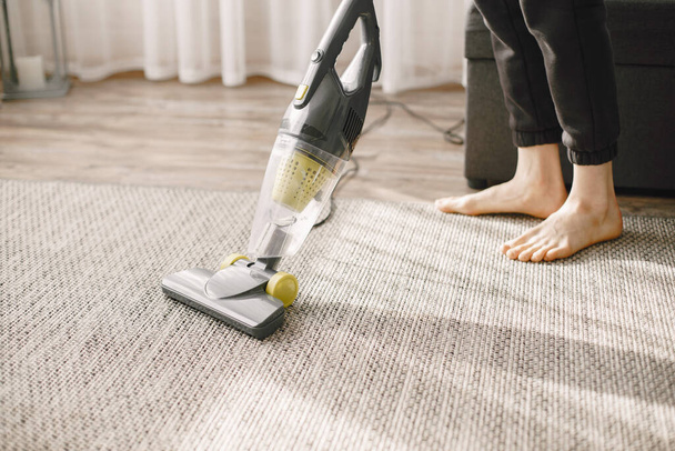Woman vacuuming mat at home in a good mood - Foto, afbeelding