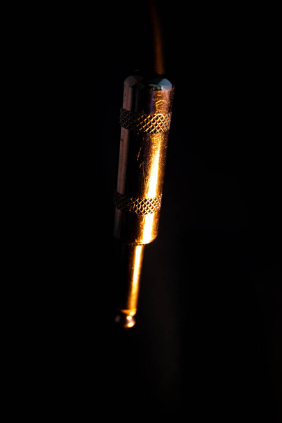 Макровоз вертикального зношеного металевого чвертьдюймового телефонного джека, ізольованого на чорному тлі з оранжевим освітленням - Фото, зображення