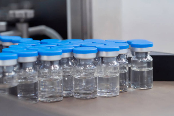 Veel medische glazen injectieflacons met blauwe toppen en vloeistof - close-up - Foto, afbeelding
