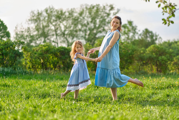 nature scene with family outdoor lifestyle. Mother and little daughter playing together in a park. Happy family concept. Happiness and harmony in family life. - Photo, image