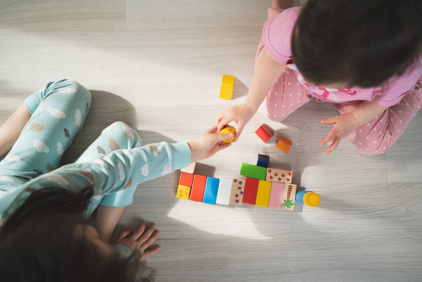 Preschool games. Children play with wooden cubes. The child passes the red cube. Kids build houses. - Foto, afbeelding