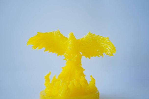 Этот миниатюрный орёл изготовлен из молочной кислоты Poly, которая разработана с использованием трехмерной печатной машины. Желтый орёл расправляет крылья на белом фоне. Миниатюрный макет. Свободное пространство для копирования. - Фото, изображение