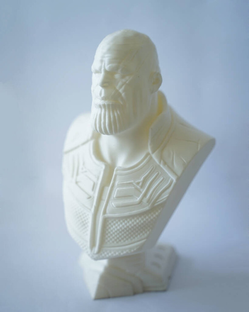 Эта миниатюра супергероя Таноса сделана из молочной кислоты Поли, которая разработана с использованием 3D-печатной машины. Танос со злобным лицом, изолированным на белом фоне. Миниатюрный макет. Свободное пространство для копирования. - Фото, изображение