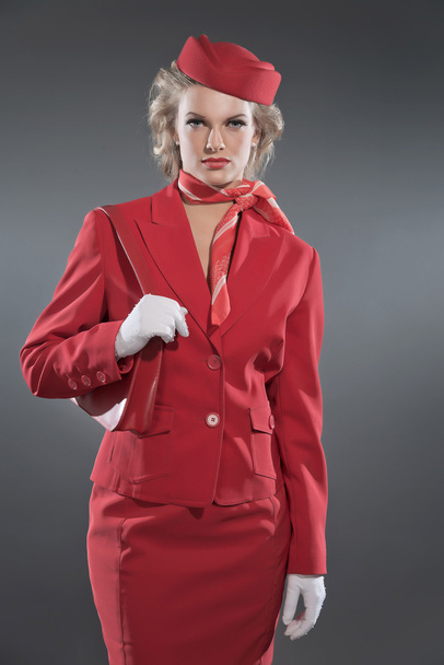 Retro blonde stewardess wearing red suit and cap. Studio shot ag - Photo, Image