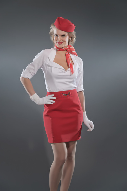 Smiling retro blonde stewardess wearing red skirt and cap with w - Photo, Image