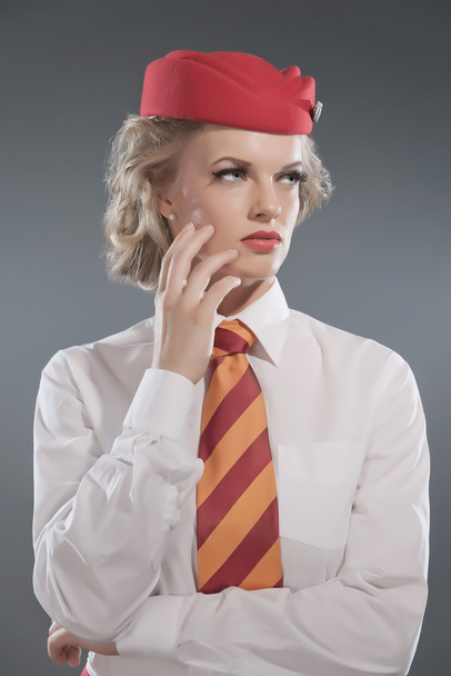 Serious retro blonde stewardess wearing red cap with striped tie - Фото, зображення