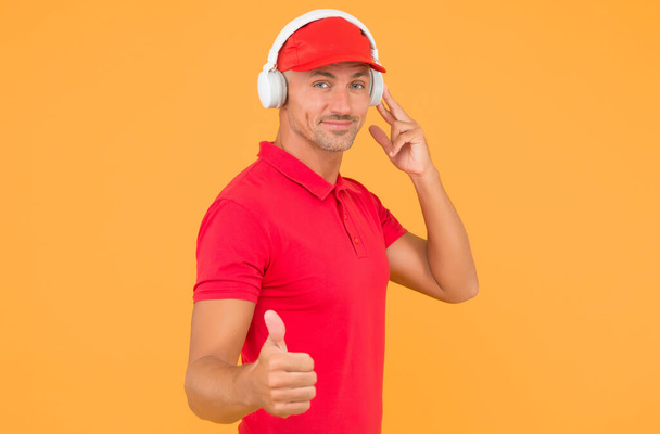 This song is so good. Unshaven man give thumbs up yellow background. Like and approval sign. Handsome guy listen to song. Modern life. New technology. Enjoying song playing in headphones - Foto, imagen