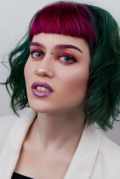 Красива жінка з фіолетовим зеленим професійним кольоровим волоссям. Яскраві очі і губи макіяж
 - Фото, зображення