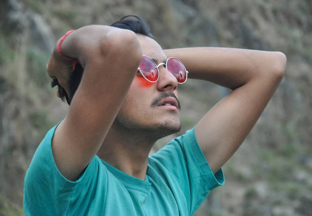 Zbliżenie na młodego faceta noszącego okulary przeciwsłoneczne i przechodzącego przez włosy - Zdjęcie, obraz