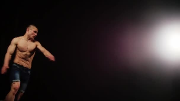Młody sportowiec robi breakdance flip w czarnym studio - Materiał filmowy, wideo