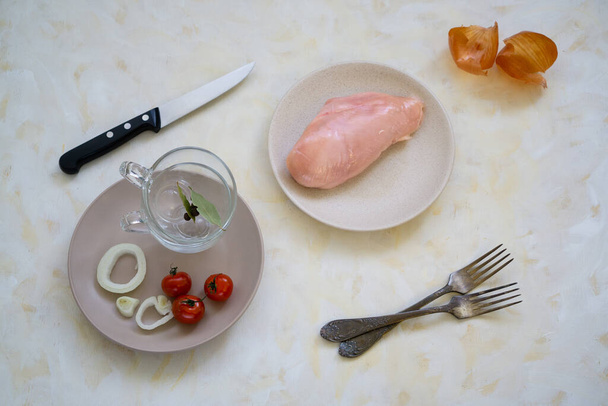Lunch cooking products for two people. Fresh chicken, cherry tomato and bay leaf with black allspice on a light kitchen countertop. - Photo, Image