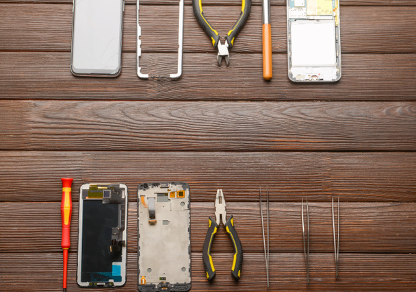 Telefones móveis desmontados com ferramentas técnicas em fundo de madeira - Foto, Imagem