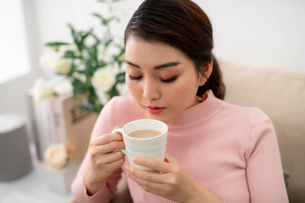 Indoor shot of a smiling asian woman drinking tea. - Фото, зображення