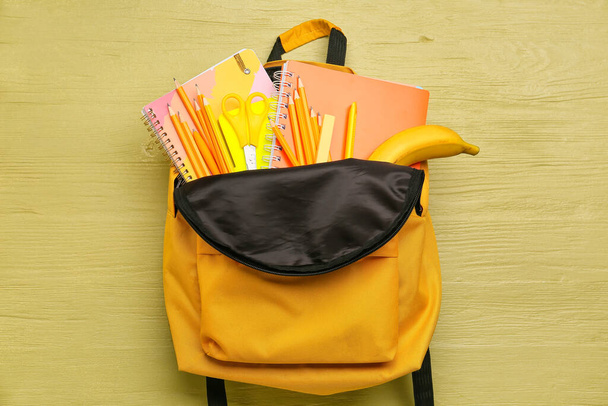 Школьный рюкзак и канцелярские принадлежности на деревянном фоне - Фото, изображение