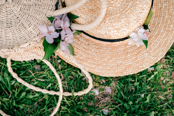 Cappello e borsa di paglia su sfondo verde. I fiori sono bianchi su fondo verde. Estate fotografia. - Foto, immagini